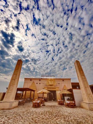a building with tables and chairs under a cloudy sky at Brother Hotel Dahab in Dahab