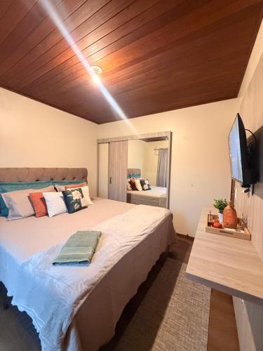 a bedroom with a large bed and a flat screen tv at Suíte Privativa in Florianópolis