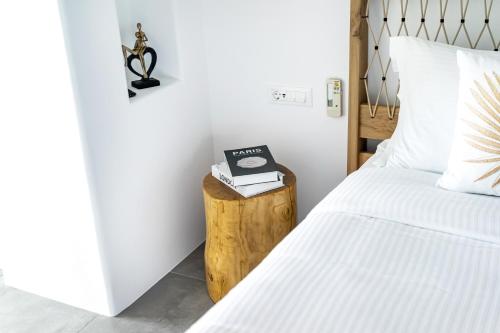 a bedroom with a bed and a table with a clock on it at Nefeli Residence & Suite Ftelia beach Mykonos in Elia