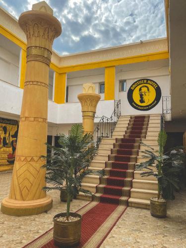 a building with stairs and palm trees in front of it at Brother Hotel Dahab in Dahab