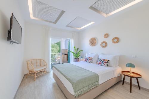 a white bedroom with a bed and a chair at The 23 Suites in Faro