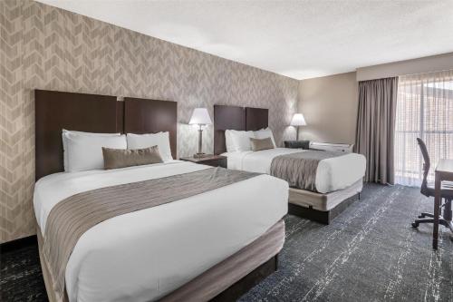 a hotel room with two beds and a desk at Best Western Plus Keene Hotel in Keene