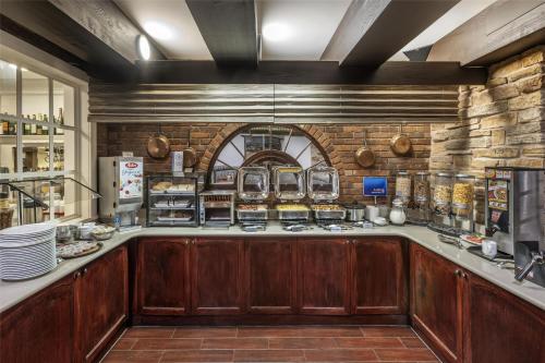 a kitchen with wooden cabinets and a brick wall at Best Western Fireside Inn in Kingston