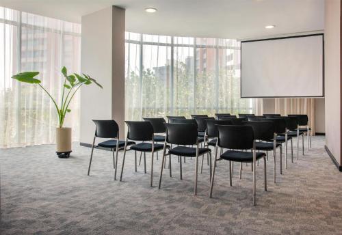 a conference room with black chairs and a screen at NH Collection Royal Smartsuites in Barranquilla