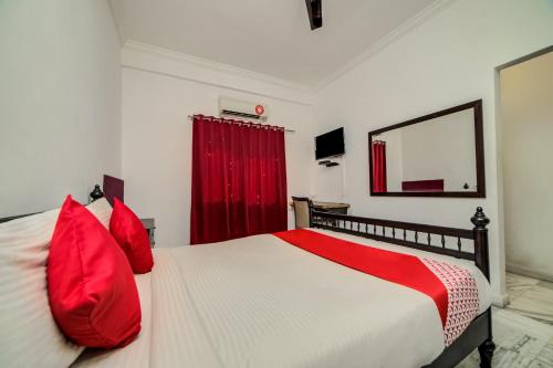 a bedroom with a large bed with red pillows at Hotel O JNTU college Near LULU mall, KPHB Colony. in Hyderabad