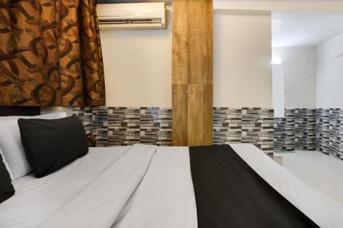 a bedroom with a white bed with a black blanket at Hotel O Kanchan Palace in Ahmedabad