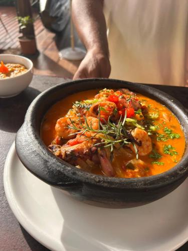 a black bowl of food on a white plate at Casa da Ilha & SPA in Abraão