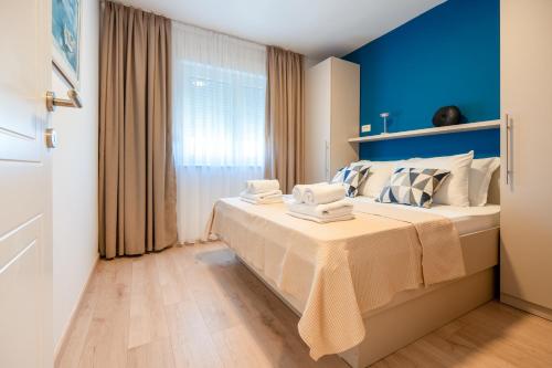 a bedroom with blue walls and a bed with towels on it at Apartman Adagio in Neum