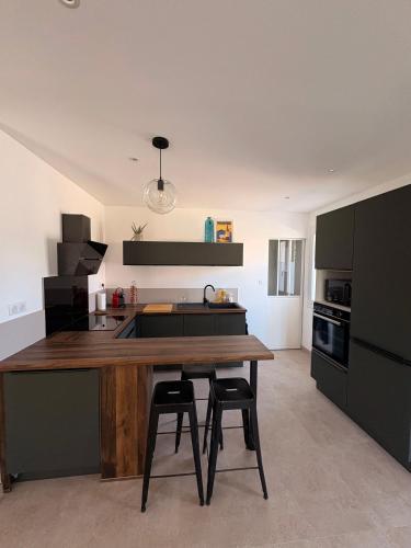 a kitchen with a wooden table and two bar stools at Maison individuelle en Provence in Pernes-les-Fontaines