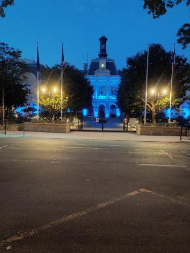 un bâtiment avec des lumières bleues allumées la nuit dans l'établissement Appartement élégant proche Paris, à Clichy