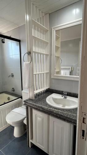 a bathroom with a sink and a toilet and a mirror at Hotel Du Lac Macaé in Macaé