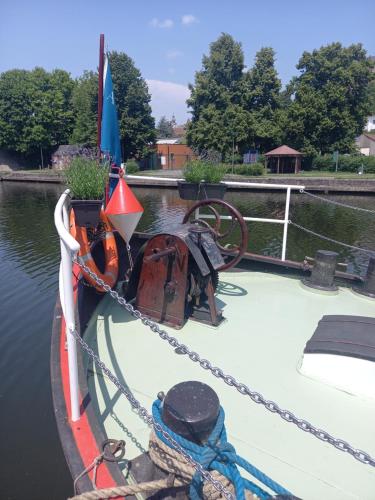a boat tied up to a chain on the water at Péniche Jeannine in Lobbes