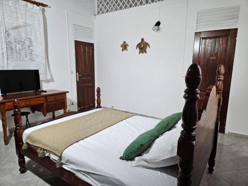a bedroom with a bed and a desk with a computer at Maison la Casa Créole, spa, emplacement central in Les Abymes
