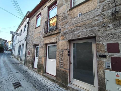 a brick building with a white door on a street at Casa Dos Passos 0 in Guarda