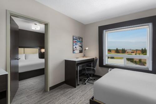 a hotel room with a bed and a desk and a window at Holiday Inn Express & Suites Cold Lake by IHG in Cold Lake