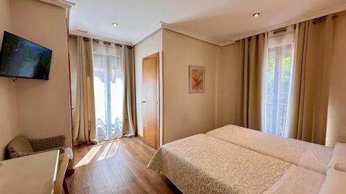 a bedroom with a bed and a tv on a wall at Hostal Toledo in Toledo
