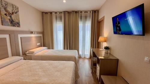 a hotel room with two beds and a flat screen tv at Hostal Toledo in Toledo