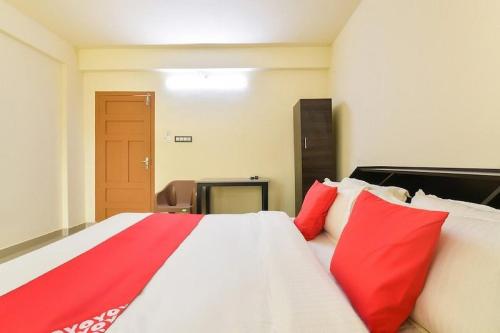 a bedroom with a large bed with red pillows at Hotel O VR Lodge in Pathanāmthitta