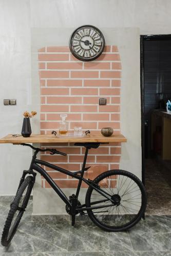 a bike parked next to a brick wall with a clock at Condo 30 in Agouévé