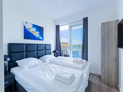 a bedroom with a large white bed and a window at Apartment in Sint-Annaland with Water Views in Sint Annaland