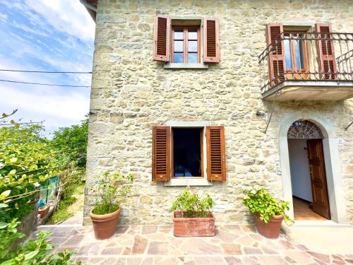 a stone building with two windows and potted plants at Villa Fiorita tra le Colline del Casentino in Chitignano