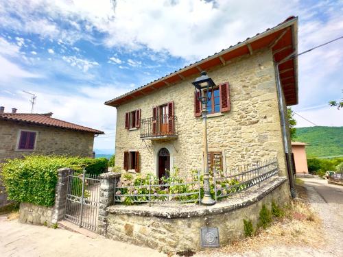 a stone house with a gate and a fence at Villa Fiorita tra le Colline del Casentino in Chitignano