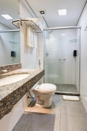 a bathroom with a shower and a toilet and a sink at Allia Gran Pampulha Suites in Belo Horizonte