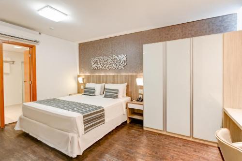 a bedroom with a large white bed in a room at Allia Gran Pampulha Suites in Belo Horizonte