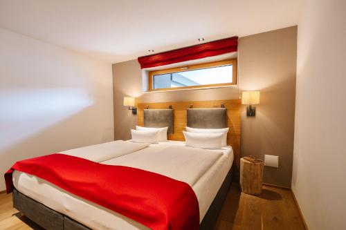 a bedroom with a large bed with a red blanket at Das.Hochgrat in Oberstaufen