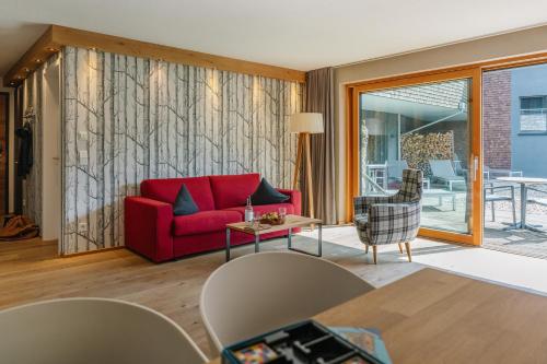a living room with a red couch and a table at Das.Hochgrat in Oberstaufen