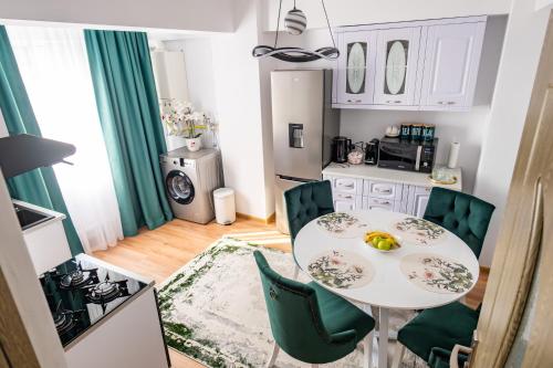 a small kitchen with a white table and green chairs at Apartament de închiriat Accommodation in Suceava