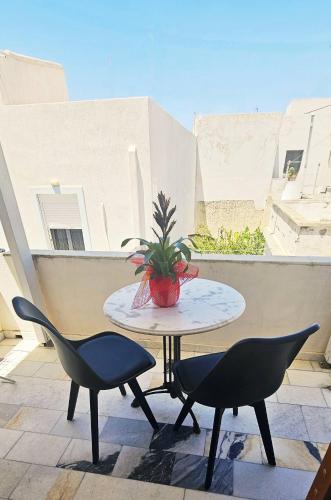 a table with two chairs and a potted plant on a balcony at Hotel Rea in Naxos Chora