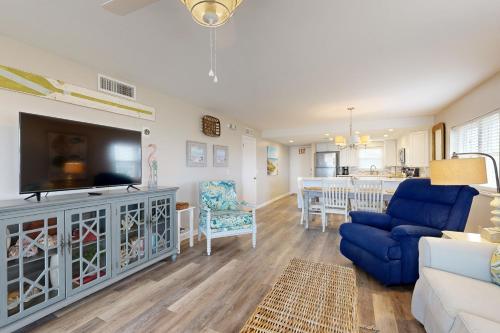 Oceanfront corner condo with sunrise-view balcony, pool & 1-minute walk to beach في فرناندينا بيتش: غرفة معيشة مع تلفزيون بشاشة مسطحة وأريكة زرقاء