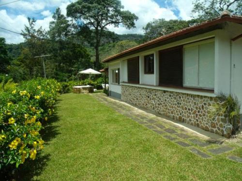 a house with a grass yard next to a building at Paraíso aconchegante em Itaipava in Itaipava