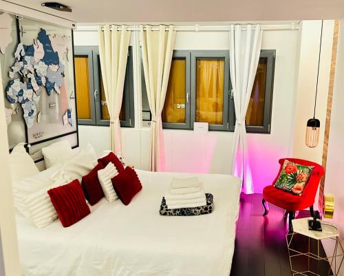 ein Schlafzimmer mit einem weißen Bett und einem roten Stuhl in der Unterkunft Private Rooftop Jacuzzi in La Celle-sous-Gouzon