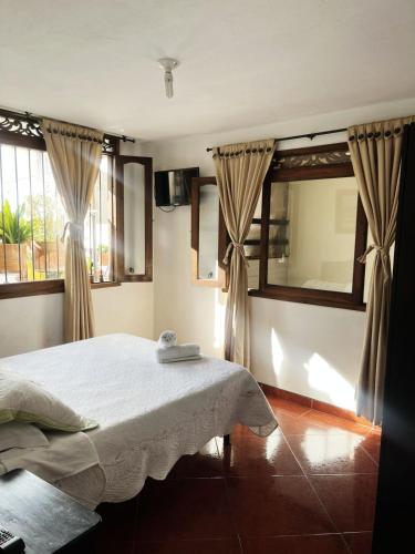 a bedroom with a bed and two windows at VILLA LEWANA 2 in Villa de Leyva
