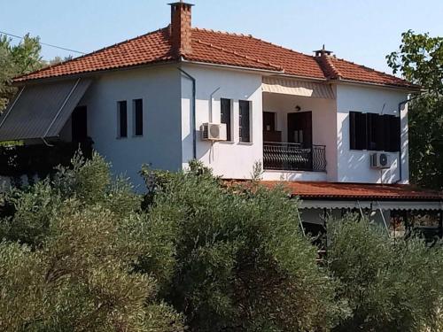 a white house with a red roof at Margianou Seaview Apartments 3 & 4 in Kálamos