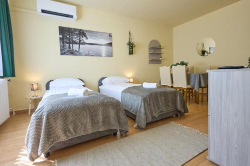 zwei Betten in einem Zimmer mit Tisch und Esszimmer in der Unterkunft Panni Apartman - belváros in Debrecen