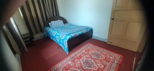 a small bed in a room with a rug and a door at Bhurban heights in Murree