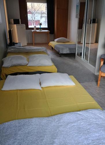 three beds in a room with yellow sheets and pillows at PitStop 6 in Tampere
