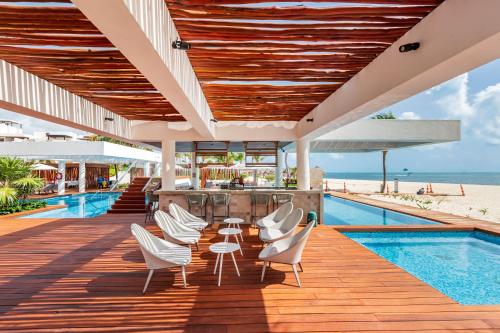 an outdoor deck with white chairs and a swimming pool at La Amada, Private Terrace Penthouse in Beachfront Complex in Cancún