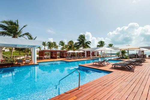 a swimming pool with chairs and umbrellas at a resort at La Amada, Private Terrace Penthouse in Beachfront Complex in Cancún