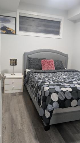 a bedroom with a bed with a black and white comforter at Cozy Escape Guest Suite in Edmonton