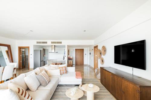 a living room with white furniture and a flat screen tv at La Amada, Private Terrace Penthouse in Beachfront Complex in Cancún