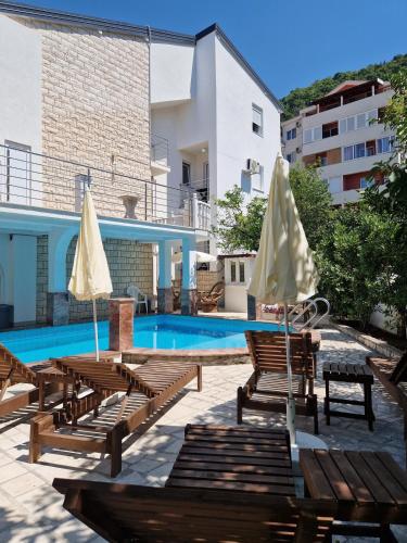 a pool with chairs and umbrellas next to a building at Villa Golf 2 in Budva