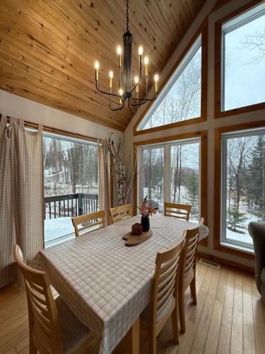 jadalnia ze stołem i kilkoma oknami w obiekcie Sandy Cove Cottage w mieście Haliburton