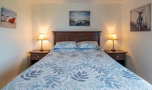 a bedroom with a blue bed with two night stands at Gite la Maison Rochefort in Baie-Sainte-Catherine