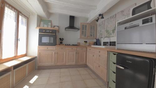 a kitchen with wooden cabinets and a black refrigerator at L'Hirondelle in Airvault