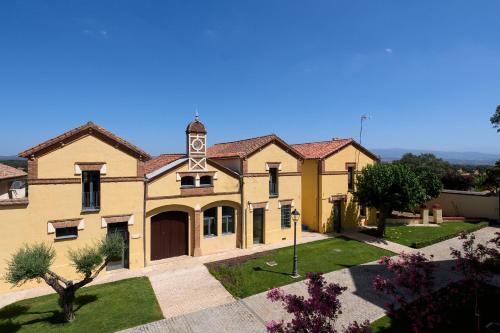 a large yellow building with a clock tower at Hotel Rural Palacio Haza de la Concepción in Malpartida de Plasencia