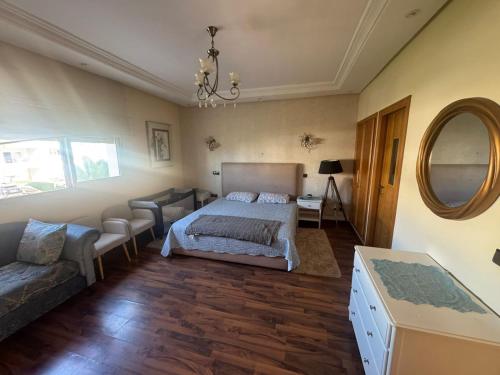 Un dormitorio con una cama, un sofá y un espejo. en Savannah beach, en Dar Hamida